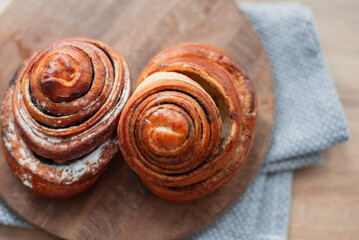 Delicious sweet buns lie on a wooden round board on the kitchen, top view. Baking