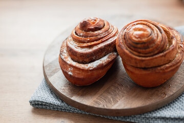 Cinnamon rolls on a wooden board in the kitchen. Delicious sweet baked goods