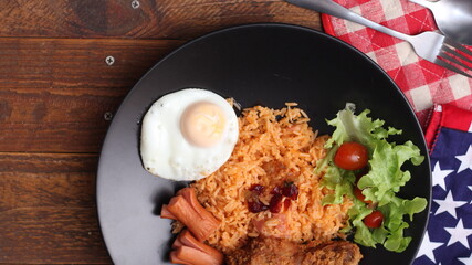 American fried rice served with sausages, cucumbers, shredded vegetables in a gray plate on a white table with seasoning.