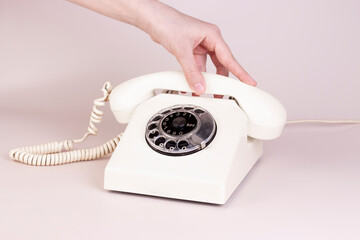 Girl hand holding vintage telephone receiver with phone on light background. Communication 80s. minimal concept.