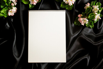 Blank open spiral sketchbook notebook and spring blooming tree branches with white flowers on...