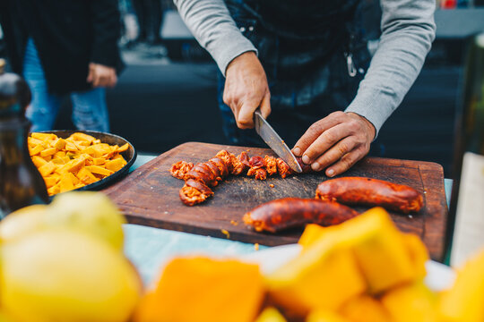 Manos de cocinero hombre picando chorizo para un locro