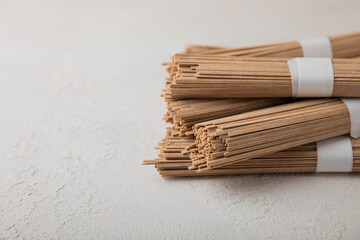 Buckwheat paste on a background of gray cement. Raw noodles. Ingredients for a gluten free dish. Dried buckwheat soba noodles. Traditional Japanese food. Healthy food. Place to copy.