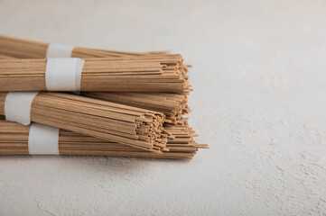 Buckwheat paste on a background of gray cement. Raw noodles. Ingredients for a gluten free dish. Dried buckwheat soba noodles. Traditional Japanese food. Healthy food. Place to copy.