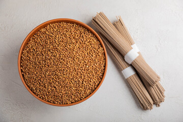 Buckwheat in a bowl with buckwheat paste on a white textured marble background. Raw buckwheat. Ingredients for gluten free cereal. Healthy food. Place to copy.
