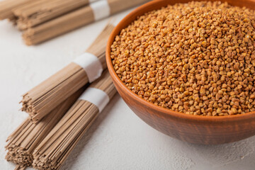 Buckwheat in a bowl with buckwheat paste on a white textured marble background. Raw buckwheat. Ingredients for gluten free cereal. Healthy food. Place to copy.