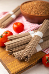 Buckwheat pasta with cherry tomatoes on a black textured marble background. Raw pasta. Ingredients for a gluten free dish. Healthy food. Place to copy.