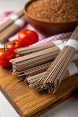 Buckwheat pasta with cherry tomatoes on a black textured marble background. Raw pasta. Ingredients for a gluten free dish. Healthy food. Place to copy.