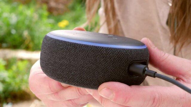 Woman holds smart home assistant voice activated in the garden