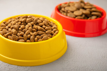 Dry food for cats and dogs in a yellow and red bowl on  cement background.Vitamins and nutrients for good health and pet energy.