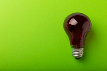 Red light bulb close-up on a green paper background. copy space. space for text.