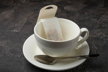 Buckwheat Tea Superfood. Close-up tea bag in a white tea cup on a black textured background. copy space.Place for text.