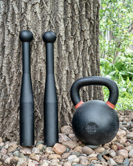 Naklejka na ściany i meble pair of steel clubs and kettlebell in backyard, functional fitness concept, heavy clubs are particularly valuable for grip strength, shoulder work, and rotational core power
