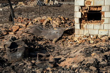 Destroyed houses as a result of a fire in Russia. Bricks and parts of walls, various household items, broken windows covered with ash lie on the surface of the earth. Natural disaster
