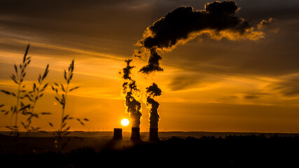 réacteurs de centrale nucléaire crachant sa fumée, au lever du soleil. prise de vue lointain sur une centrale nucléaire, en contre jour