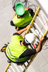electrician worker on staircase installing optical fiber cable for internet and telephone lines in city street