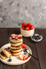Fresh pancakes laid out in a stack, decorated with fresh berries, sprinkled with powdered sugar, beautiful serving