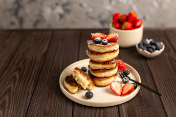 Fresh pancakes laid out in a stack, decorated with fresh berries, sprinkled with powdered sugar, beautiful serving