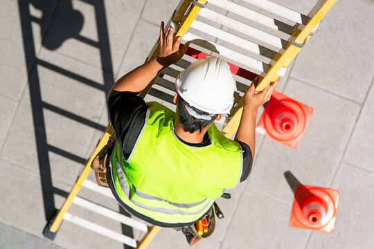 electrician worker on staircase installing optical fiber cable for internet and telephone lines in city street