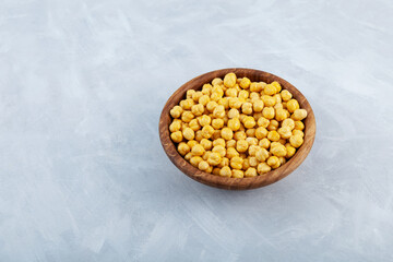 Leblebi or Roasted Chickpeas in wooden bowl on grey background. Turkish snack. Selective focus, copy space