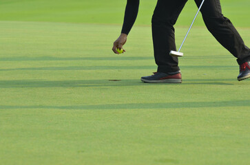 Unidentified golfer pick up golf ball from a hole.