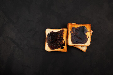 Hot toasted bread for breakfast. Roasted Aussie savory toasts with vegemite spread. Vegemite is a very popular yeast based spread in Australia. Dark background, copy space