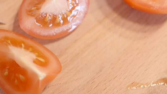 Close yup of woman hands using kitchen knife cutting fresh tomato on wooden cutting board. Action. Healthy eating concept.