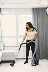 African american woman using vacuum cleaner at home