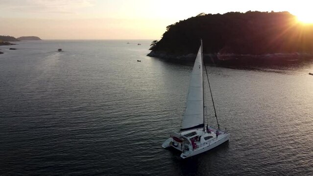 Sailing catamaran with a raised sail with tourists on board, top view of a sailboat during a sea voyage