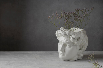 Ancient Greek sculpture. Minimal art poster. White copy plaster statue of the head of David on a gray concrete background. Copy space