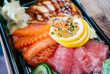 Fresh sashimi combo with lemon in a plastic plate. Food delivery.