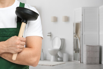 Plumber holding plunger in bathroom, closeup. Space for text