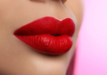 Woman with beautiful perfect lips after permanent makeup procedure on pink background, closeup
