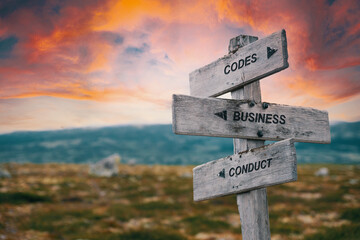 codes business conduct quote caption text written engraved on wooden signpost outdoors in nature with dramatic red skies.