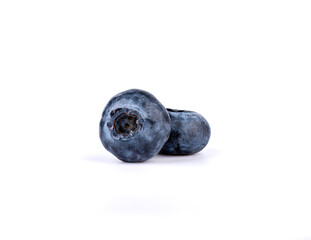 Closeup of two ripe blueberries on a white background.