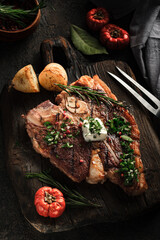Porterhouse grilled steak or Florentine beef steak with butter on a cutting board with seasonings...