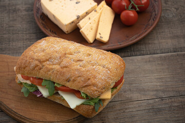 Homemade ciabatta sandwich with tomatoes and cheese on table