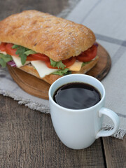 Cup of black coffee and homemade ciabatta sandwich