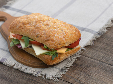 Homemade ciabatta sandwich served on a board on a wooden table