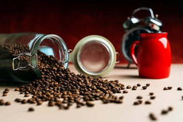 A large can of coffee beans is poured out of it. Near a glass and a clock - obrazy, fototapety, plakaty