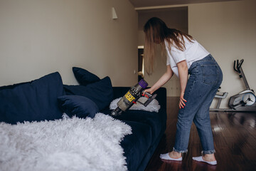 girl cleaning the sofa with a vacuum cleaner