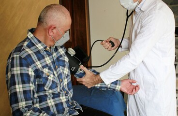 Médico accionando tensiómetro para medir presión arterial en paciente adulto - obrazy, fototapety, plakaty