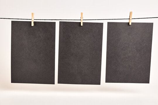 Sheets of black paper hung with clothespins on a rope on a white background. Black background for inscriptions or advertising images.