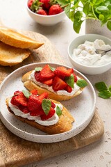 Bruschetta with goat cheese or ricotta witn strawberry and basil. Appetizer with berries. Summer healthy breakfast. Selective focus.