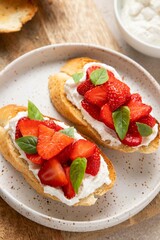 Bruschetta with goat cheese or ricotta witn strawberry and basil. Appetizer with berries. Summer healthy breakfast. Selective focus.