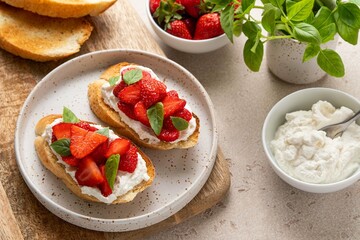 Bruschetta with goat cheese or ricotta witn strawberry and basil. Appetizer with berries. Summer healthy breakfast. Selective focus.