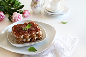 Tiramisù al caffè. Tiramisù classico al caffè con savoiardi e crema al mascarpone su un piatto bianco su fondo bianco. Dolce italiano.