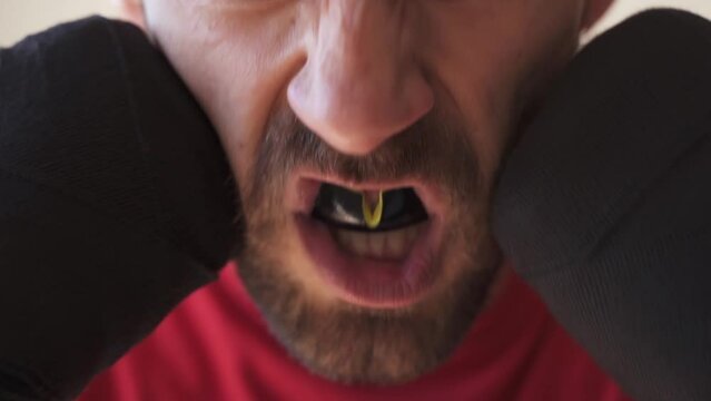 Angry and motivated male fighter shows off his mouthguard before fight in slow motion