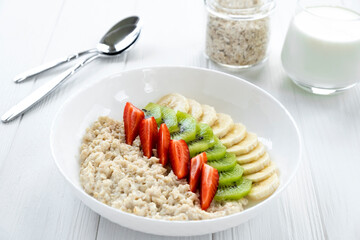 Colorful vitamin breakfast of oatmeal with fresh fruits, strawberry, banana, kiwi. Recipe of healthy meal, clean eating.