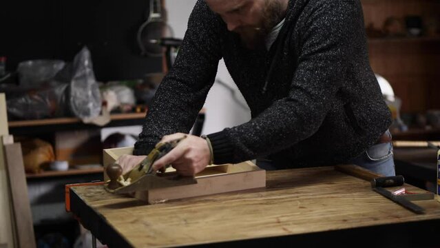 carpenter in the workshop makes furniture with a hand tool with hand plane